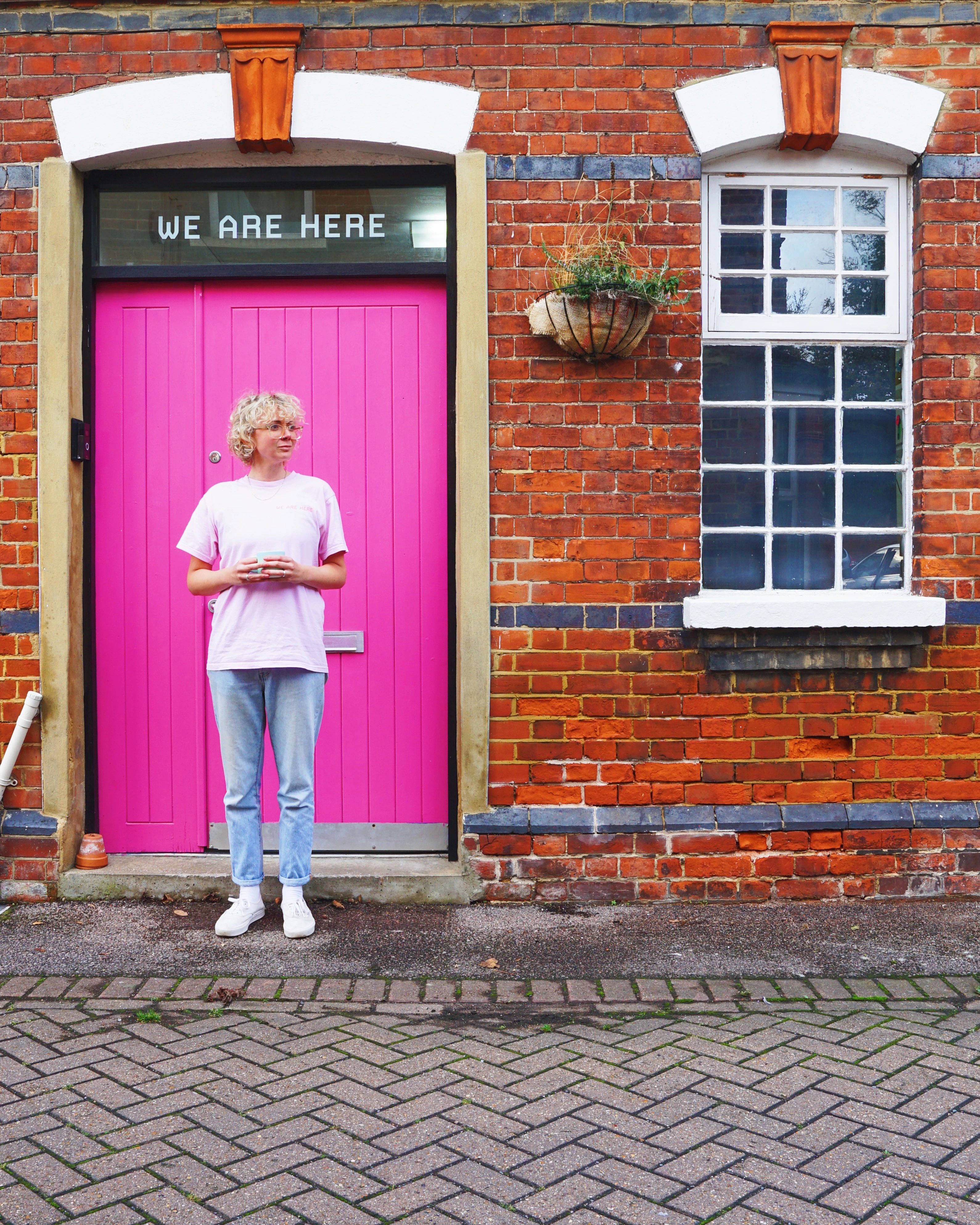 Founder, Em - standing in front of We Are Here's roastery (and a very pink front door)