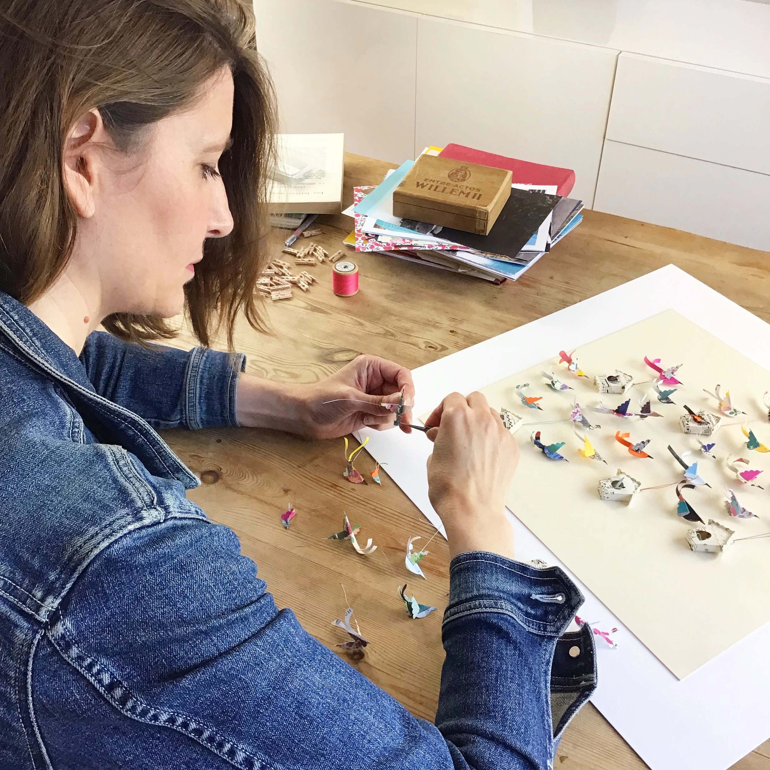 Paper artist Lucy Dorothy working in her studio creating paper birds