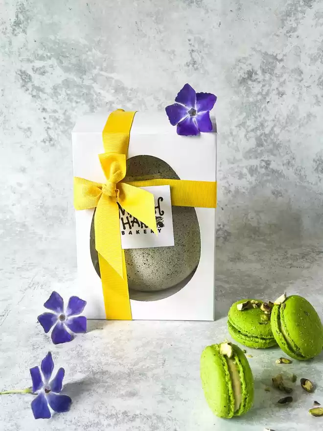 Pistachio green speckled easter egg with green macarons in a gift box with flowers
