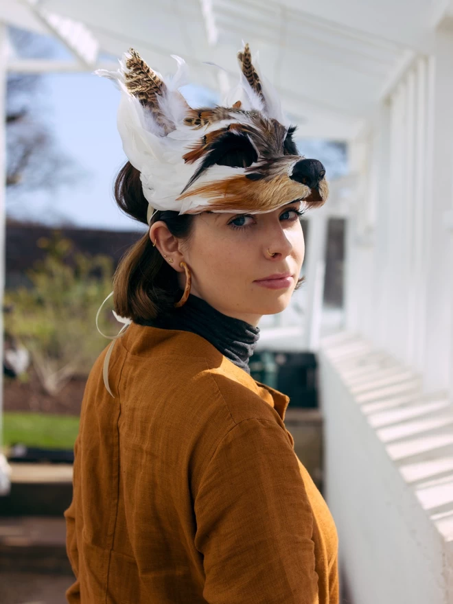 A woman wearing a luxury brown and white wolf masquerade mask atop her head as a headdress