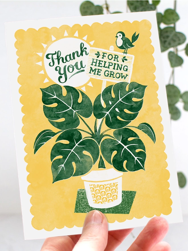 hand holding yellow and green teacher thank you card with green pot plant and bird