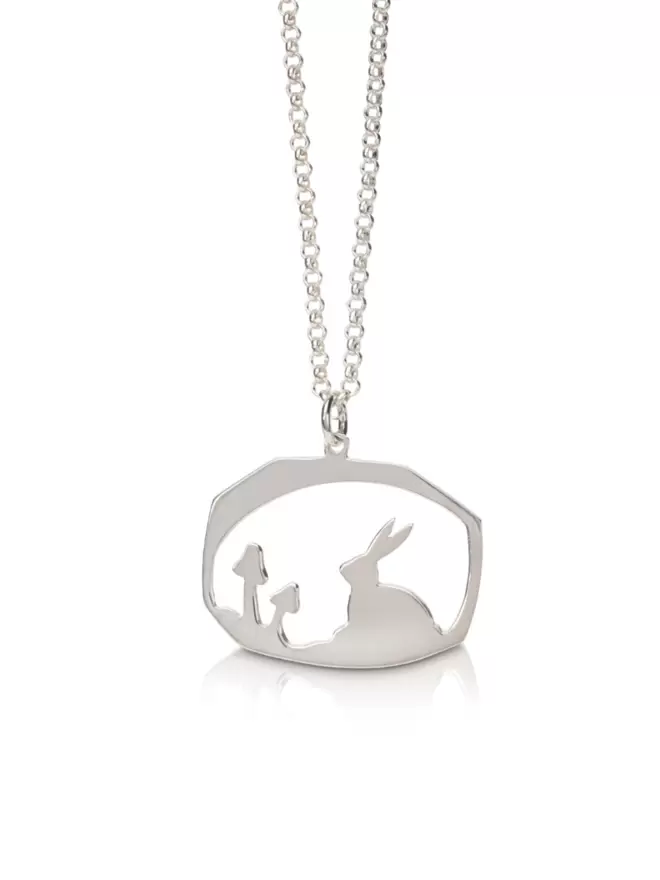 Close up of silver pendant showing rabbit and nature scene