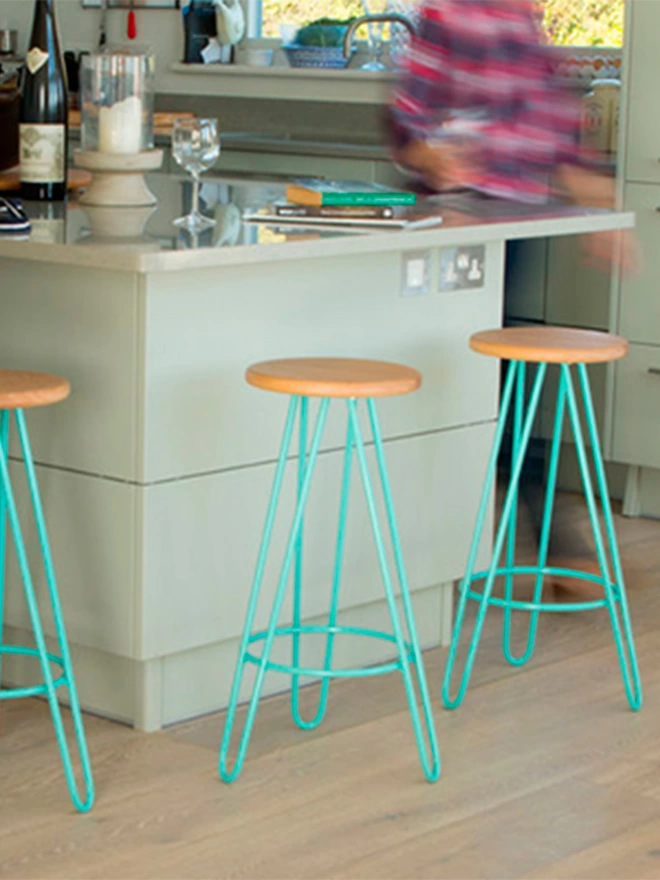 hairpin leg bar stools with cherry wood seats and turquoise legs against a kitchen island