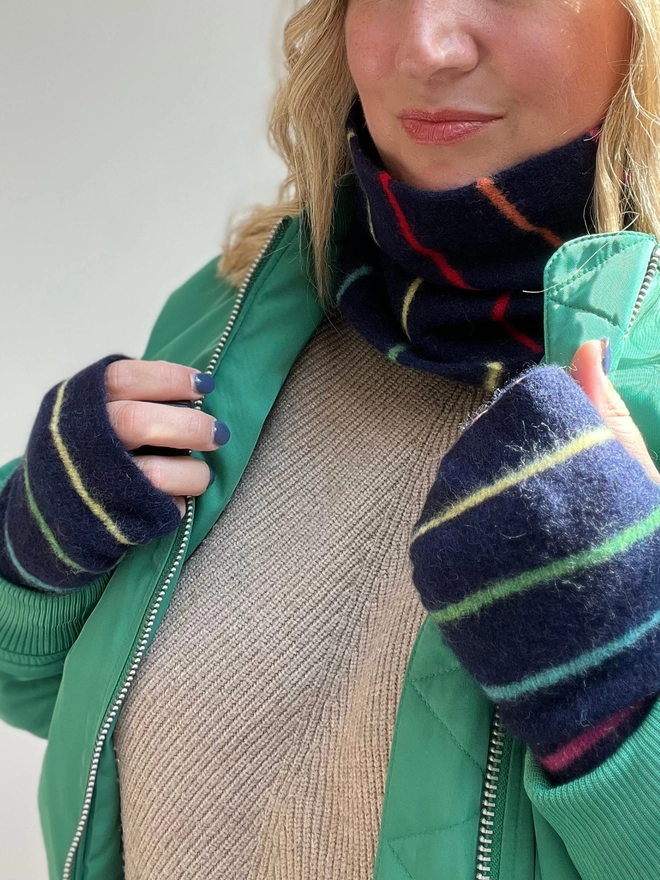 Knitted navy wristwarmers with multi coloured stripes shown worn with matching snood