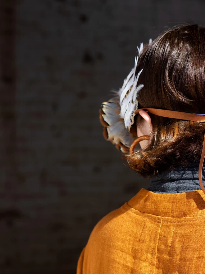 Back of woman's head wearing a luxury owl party mask