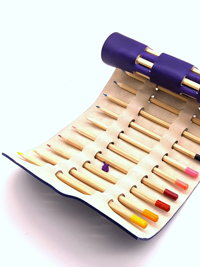 Open purple leather pencil roll, showing pencils inside.