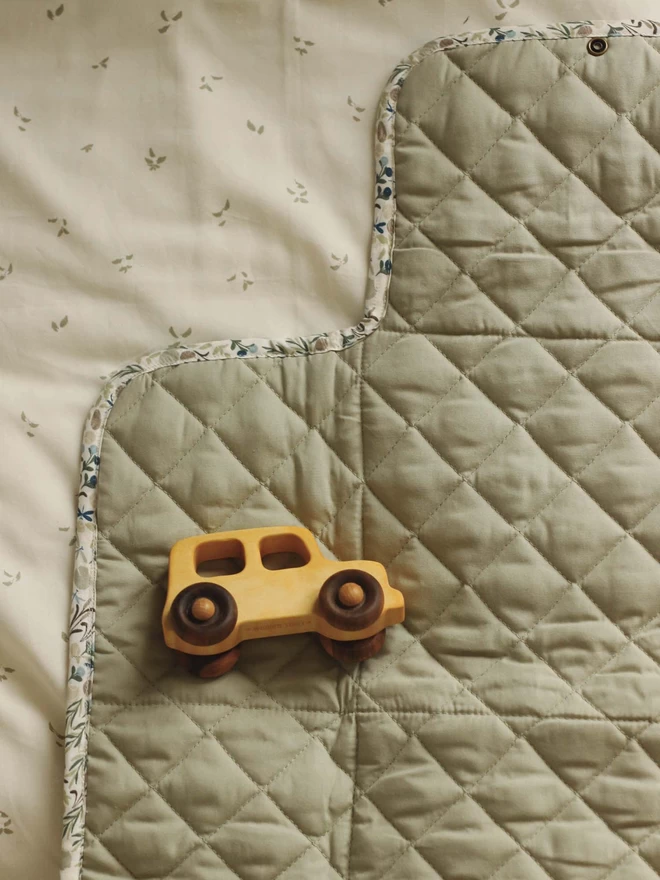 A little toy car placed on a travel changing mat in riverbank print