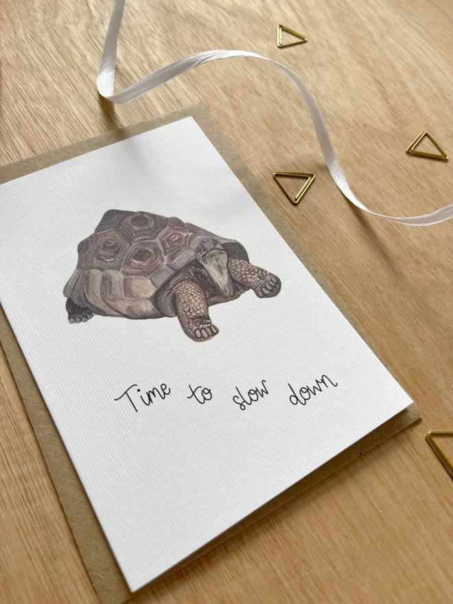 a simple greetings card featuring a tortoise with the phrase “Time to slow down”