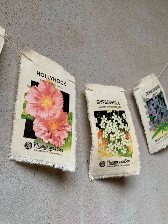 A length of flower seed packet bunting with hollyhock, gypsophila and stocks