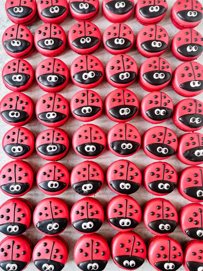 a bunch of red ladybug macarons arranged in a row