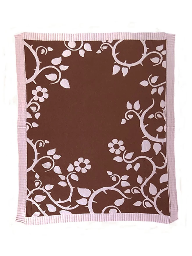 Product shot of the reverse of the blush briar rose junior blanket, chocolate brown background with pink trailing thorn floral design.