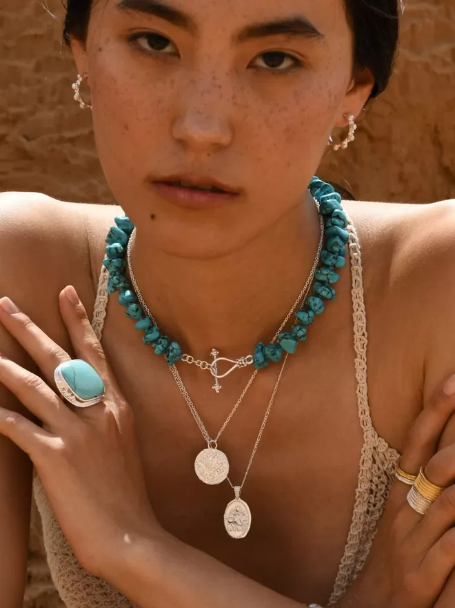 Model wearing boho silver layering necklaces with chunky turquoise choker and large turquoise ring