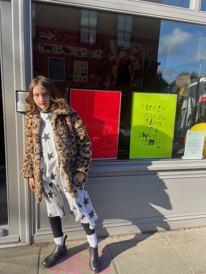 Piper in front of her screen prints in a shop window
