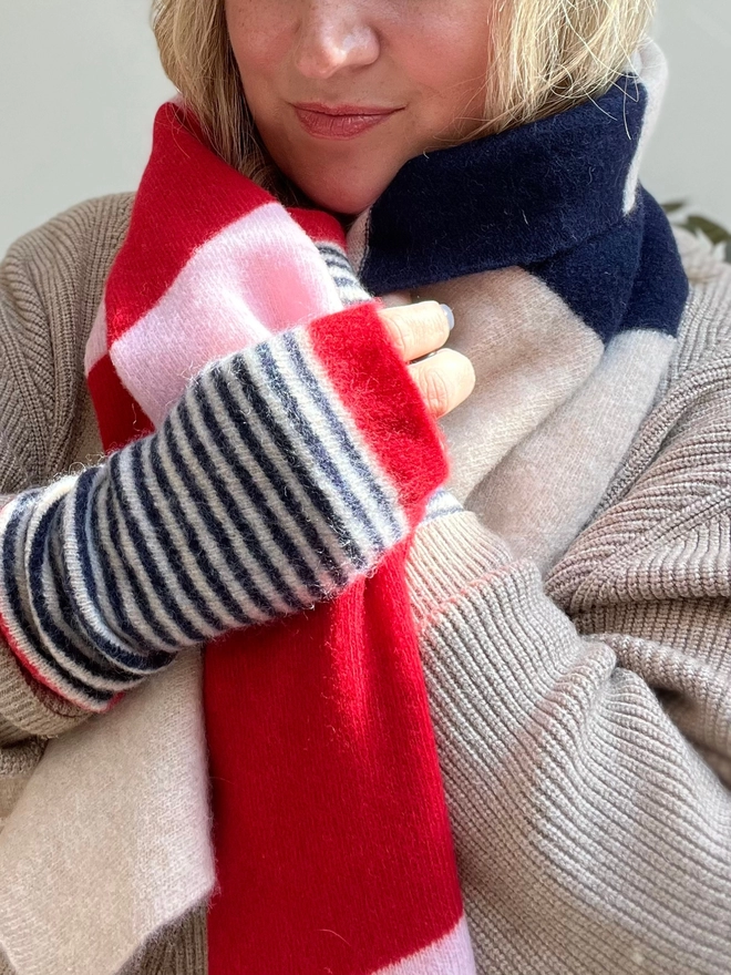 Knitted wristwarmers in red and navy being worn with matching scarf