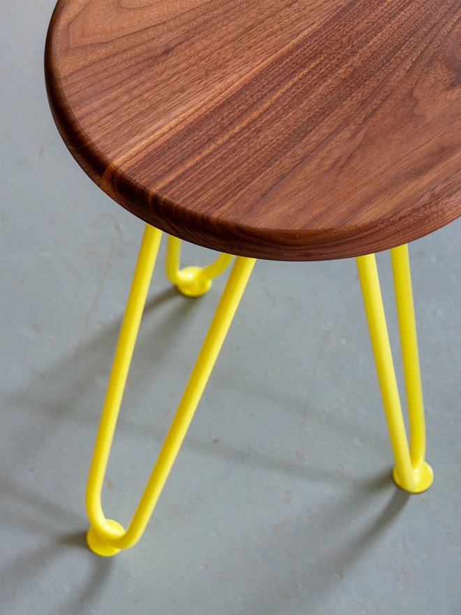 top down view of a hairpin leg stool with walnut wood seat and yellow legs
