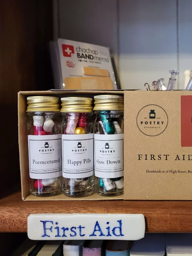 Cardboard box containing 3 glass bottles of poetry pills, on Poetry Pharmacy shelves