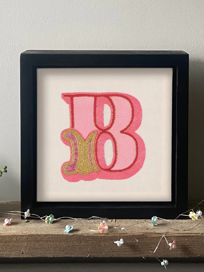An embroidered letter B in a box frame