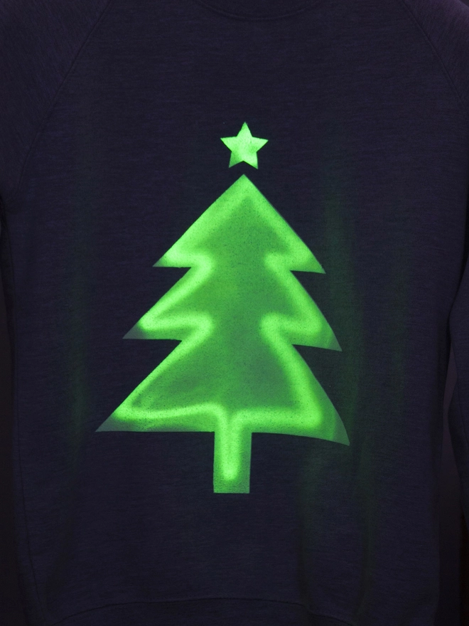A graphic of a glow in the dark xmas tree printed onto a jumper
