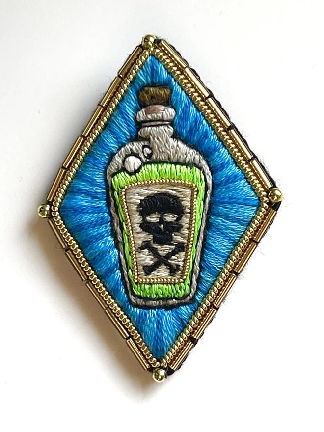 Poison bottle brooch on white background