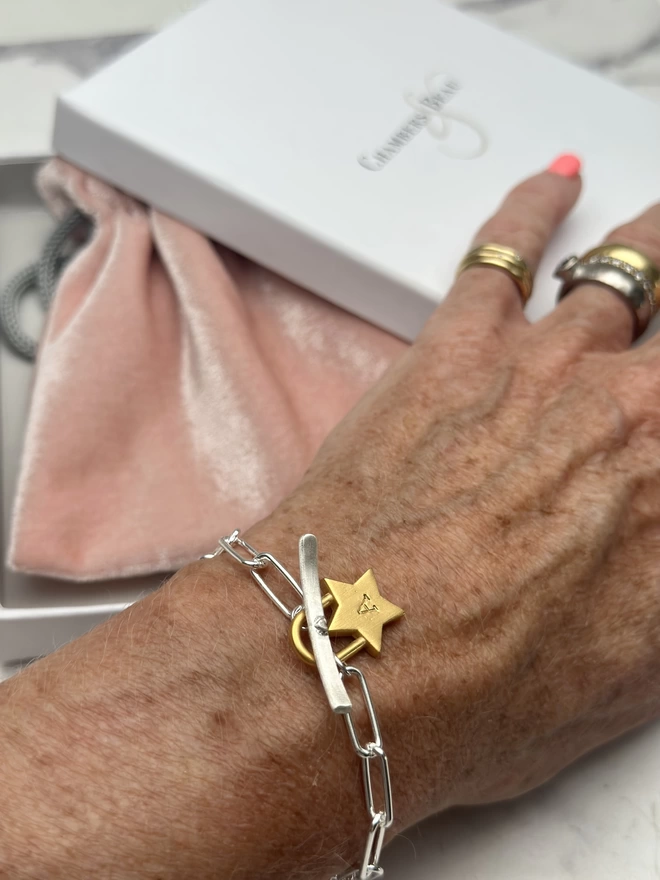 model wears a sterling silver paperclip bracelet with T bar fastener and personalised chunky gold star padlock charm. with gift box and pouch