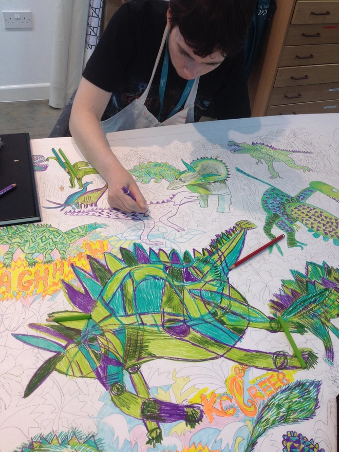 artist drawing original artwork for  dinosaurs sustainable insulated charity water bottle