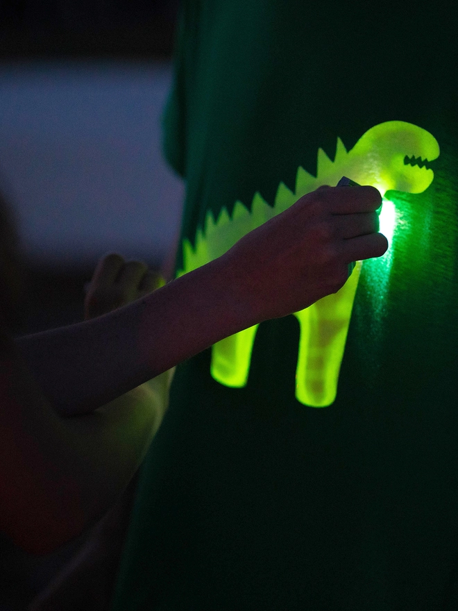 Close up of hand drawing light onto dinosaur glow tshirt