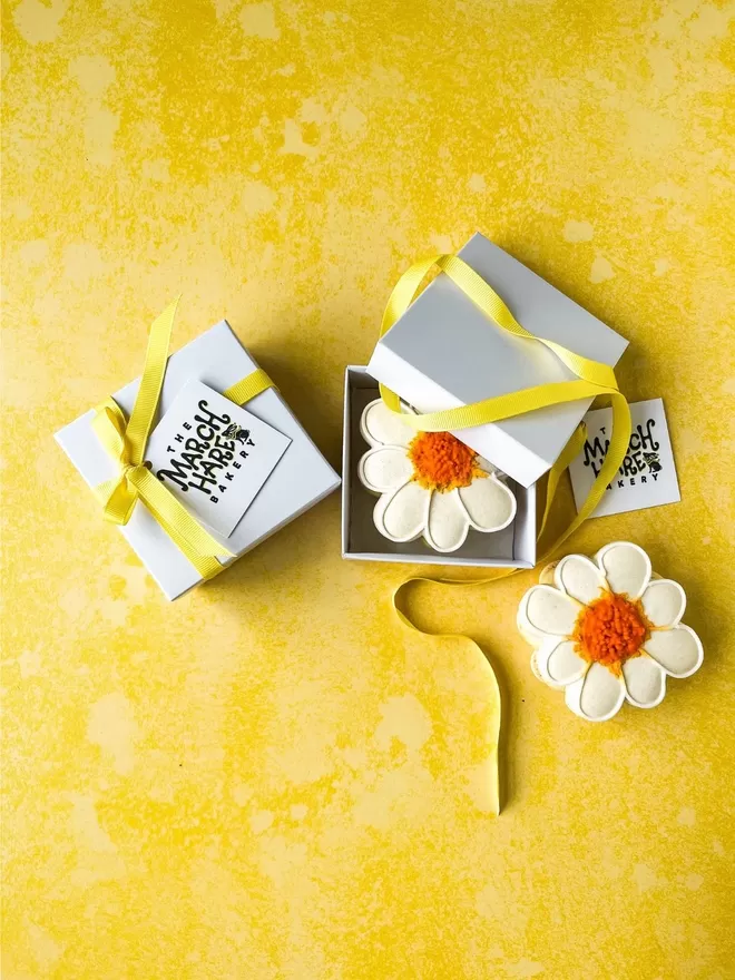 a small gift box with a daisy macaron on a yellow background