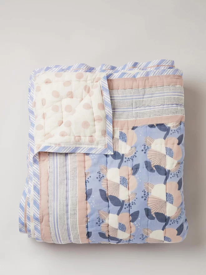 Blue floral block printed quilt with pink spot on the reverse side
