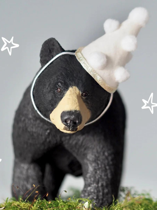 Giant Black Bear seen with a white party hat with white pom poms.