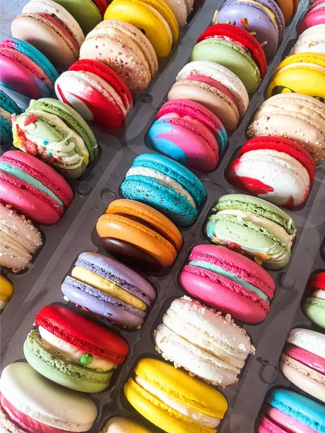 an assortment of colourful macarons in a clear tray