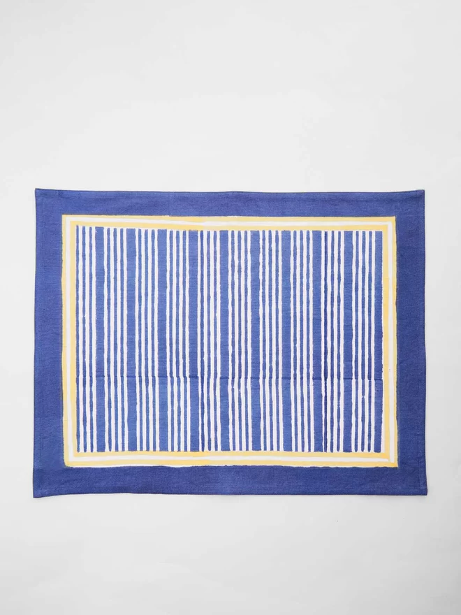 Navy and white block printed tablemat in a stripe design with yellow border 