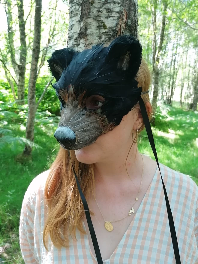 A woman wearing a luxury black bear party mask down over her face