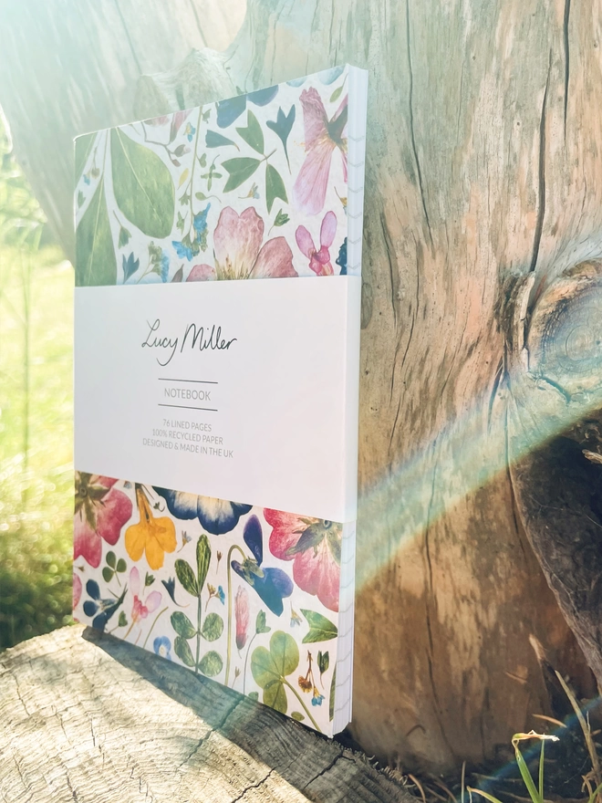 Nature-Inspired Notebook with Detailed Pressed Flower Print Cover, Branded Lucy Miller Belly Band, Leaning on Tree Stump