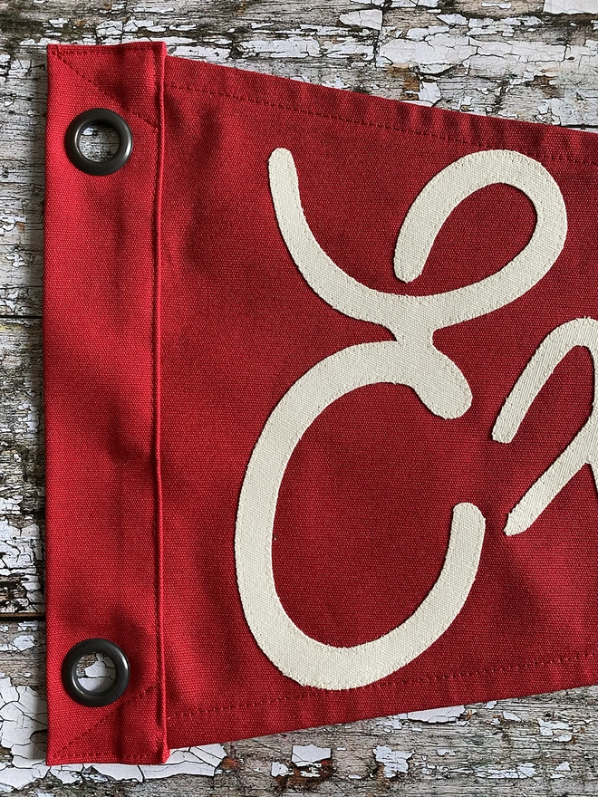 Detail of a red pennant flag showing the letter E in ivory canvas from the word Explore