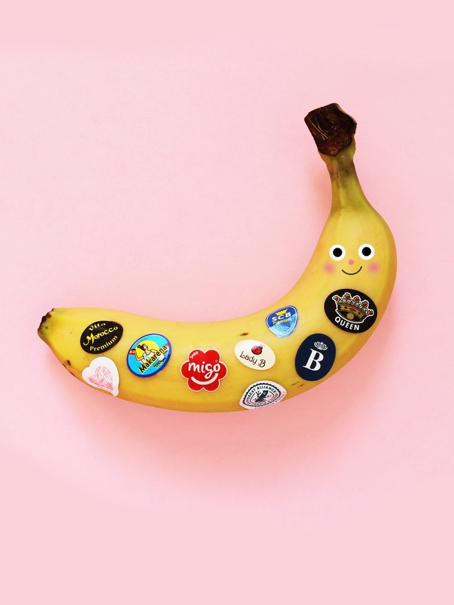 Happy Banana with fruit stickers on a pink background 