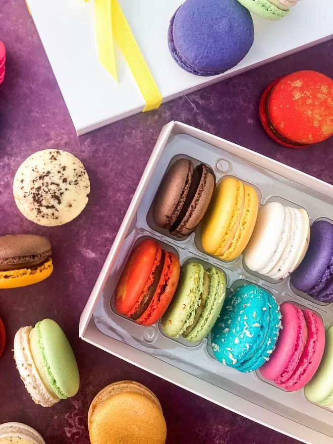 colourful macarons in a white gift box on a purple background