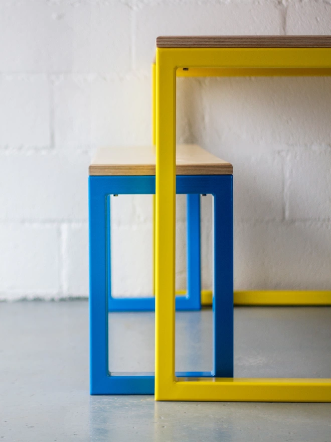end view of chunky blue bench frame and yellow table frame of a contemporary nola dining set