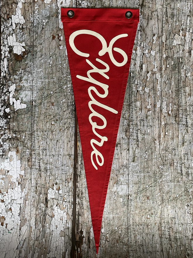 A red canvas pennant flag with the word Explore written in Ivory canvas