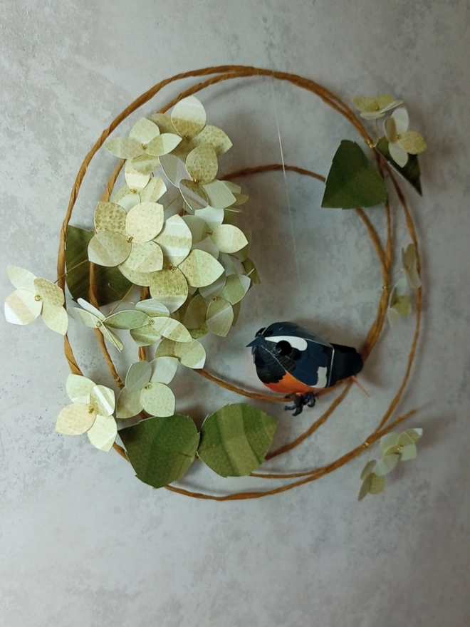 side view of a redstart sculpture perched on a hydrangea wreath