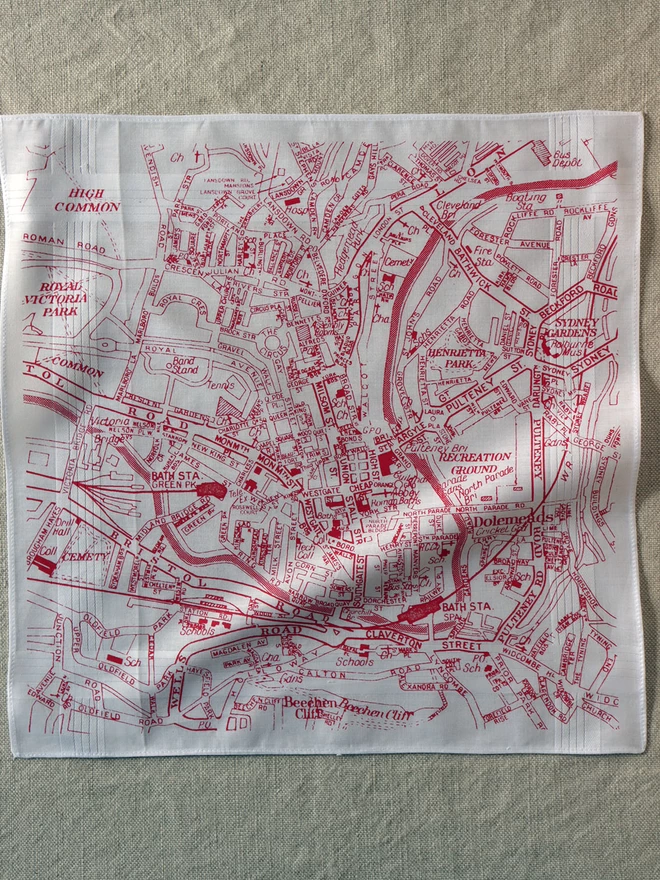 A Mr.PS Bath hankie printed in red laid flat on a linen cloth
