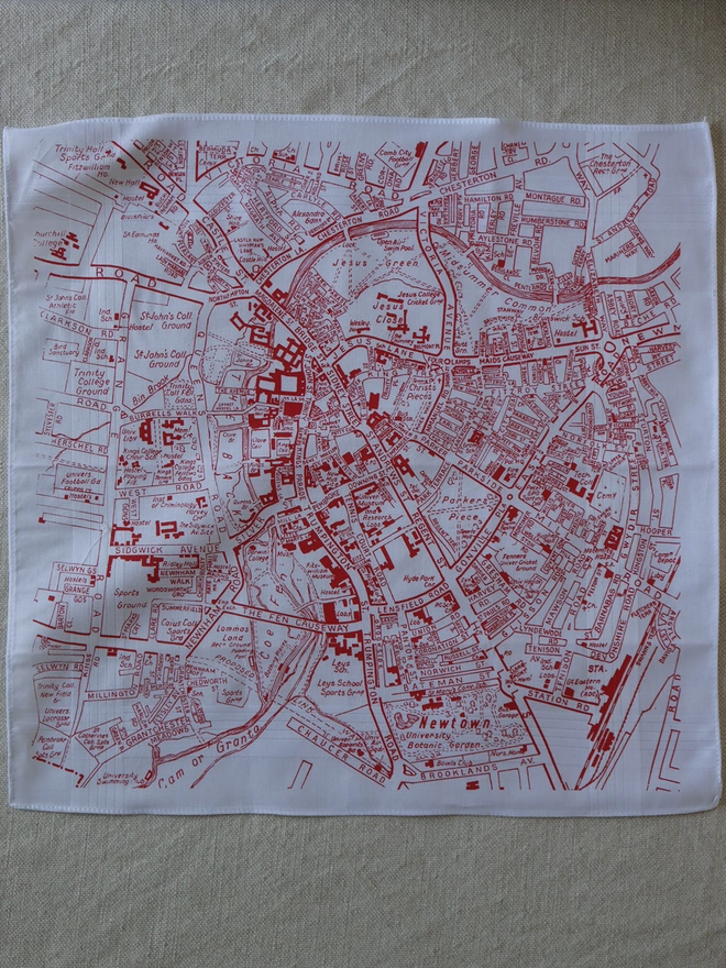 Mr.PS Cambridge map hankie in red laid on a linen tablecloth