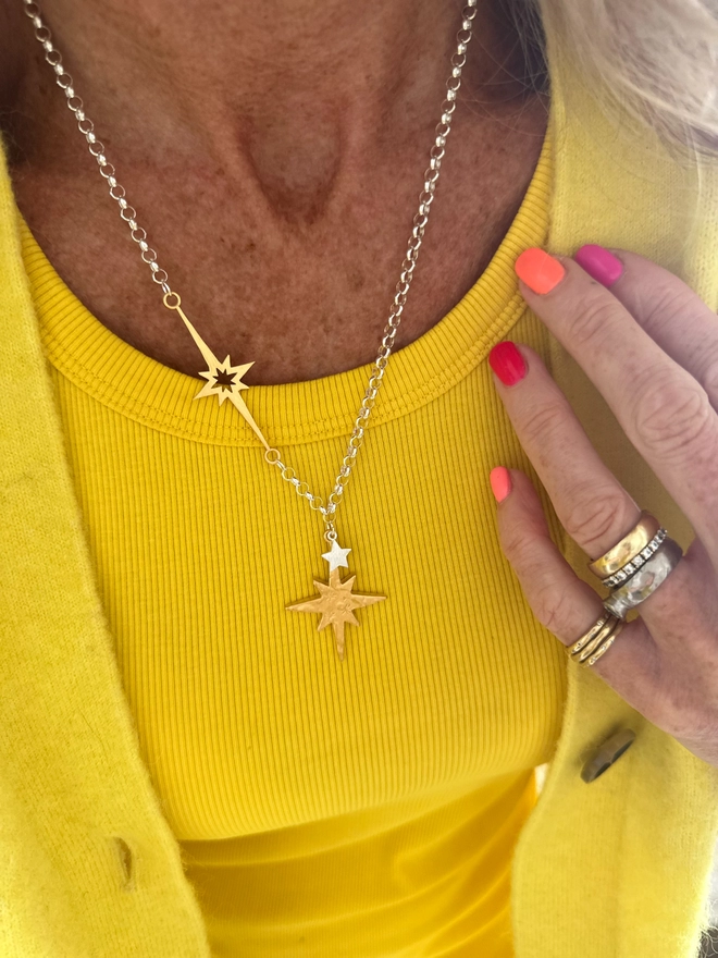 model wears gold north star and overlaid mini star in silver on a sterling silver chain, with linked supernova charm in gold 