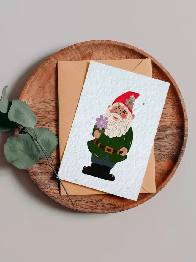 Seeded Paper Greeting Card featuring a garden gnome illustration on a wooden tray next to a Eucalyptus branch