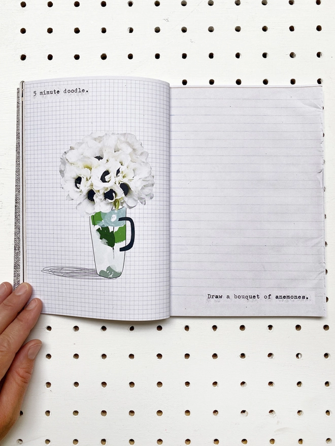 open book with instructions, flower drawings and aged paper pages on white pegboard 