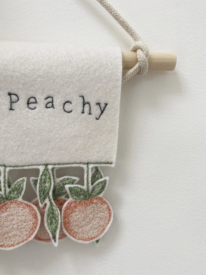 close up of the word peachy and embroidered peaches on everything's peachy banner.