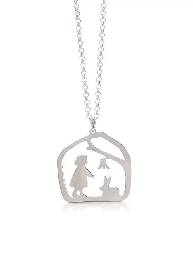 Close up of silver pendant showing child and rabbit in nature