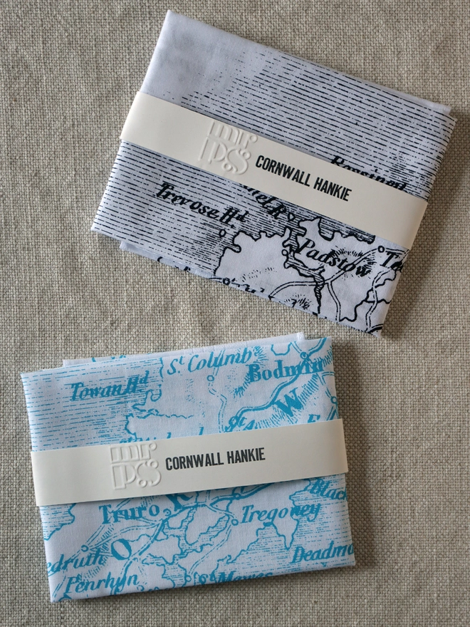 Two folded Mr.PS Cornwall county map hankies to show the colour options available: black and aqua