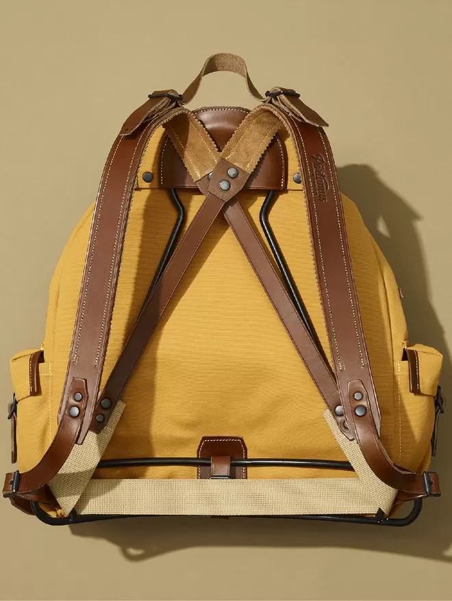 Back view of yellow Rockness backpack showing black frame, brown leather trim and black hardware.