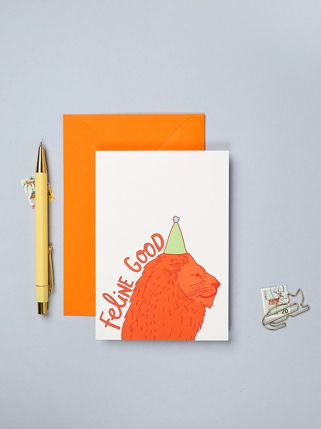 Colourful birthday card featuring a hand-drawn lion in a party hat and the words 'feline good'