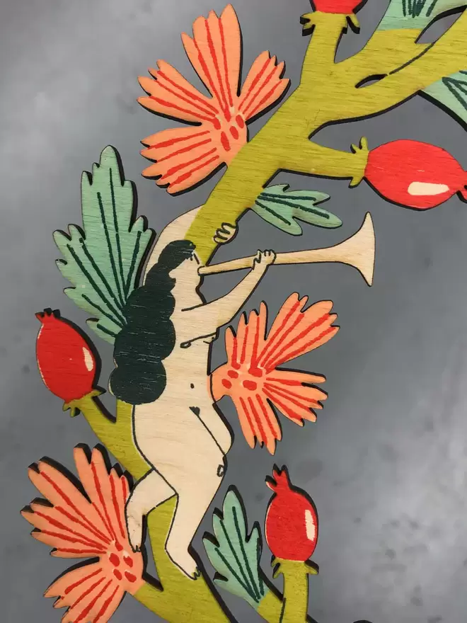 A close up of the colourful wreath, showing rosehips and a tree nymph blowing a trumpet,